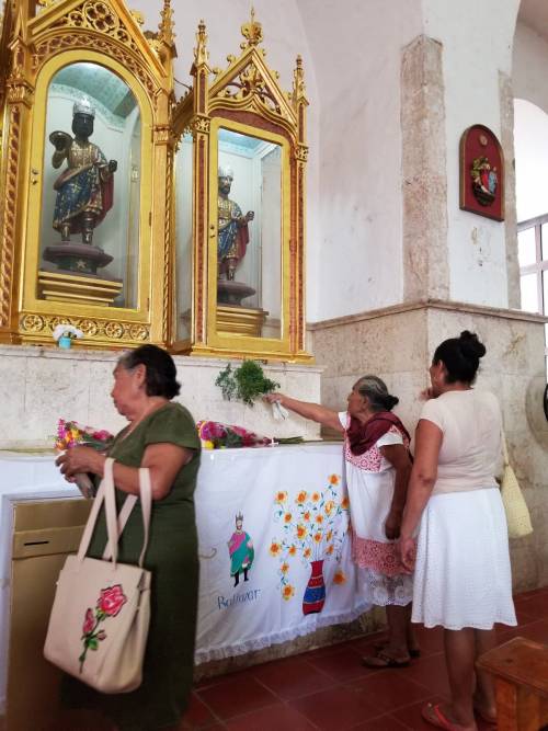 three women giving flowers at a memorial at a church in mexico